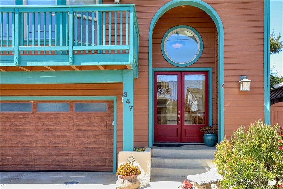 Arched front entry with porthole window and red double doors.